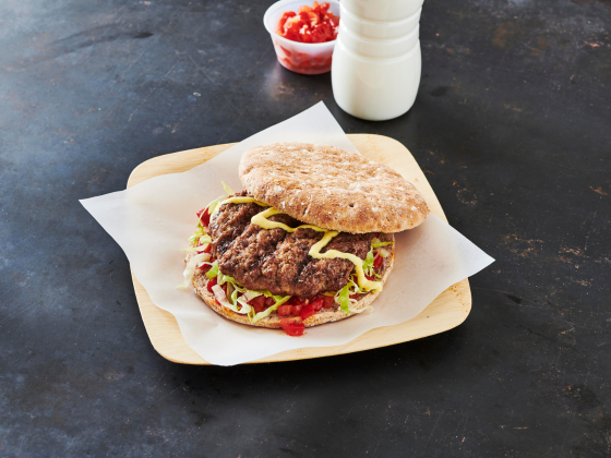 Burger on flat bread plated with a side of ketchup