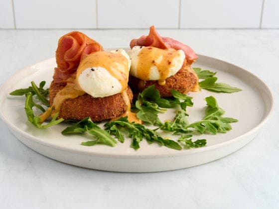 Crispy Risotto Benedict Over Greens on a White Plate