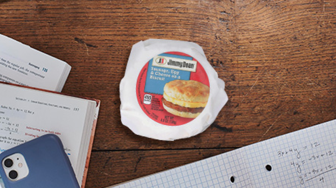 Sandwich on a desk with text books and a cell phone