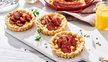 Three tarts with sausage plated in a white board