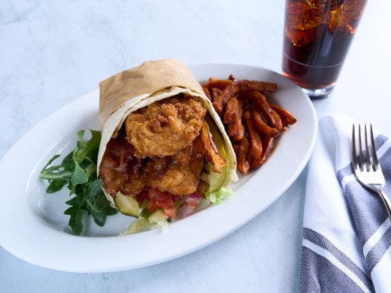 Big pickle wrap with side on fries on a white plate