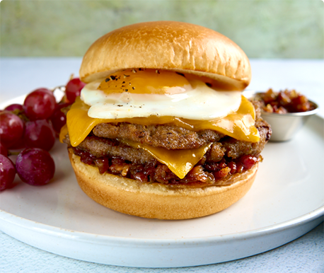 Breakfast Smash Burger with Egg  and Cheese with a Side of Grapes on a White Plate