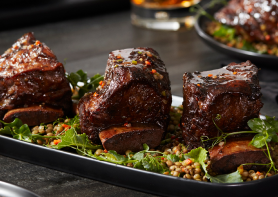 Rib short ribs plated on a bed of greens