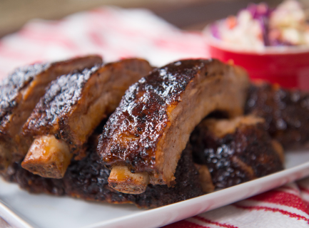 Baby back ribs on a white plate with a side