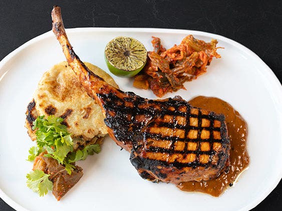 Pork Bulgogi With Potatgo Cakes, Half Lime and Sides Served on a White Plate