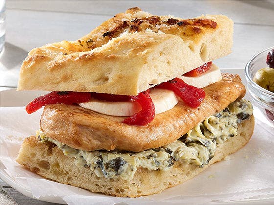 Chicken sandwich with roasted red peppers, mozzarella cheese, spinach and artichoke spread on focaccia bread