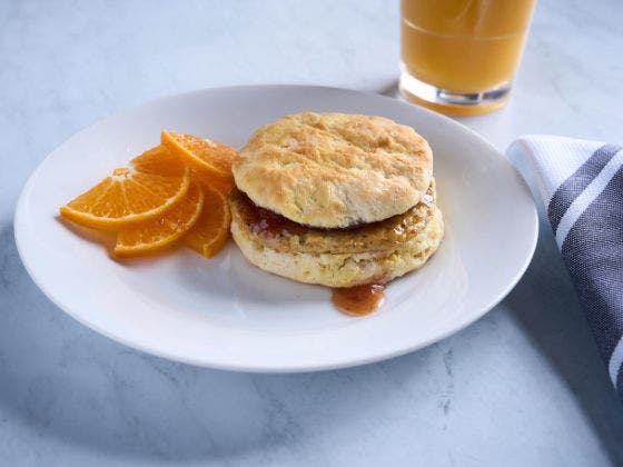 Plated chicken patty biscuit with chipotle strawberry jam and orange slices