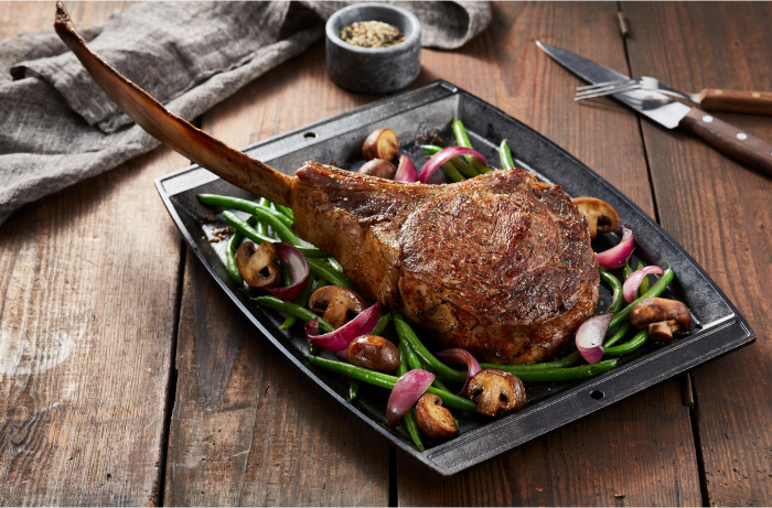 Tomahawk Steak in a bed of vegetables on a plate