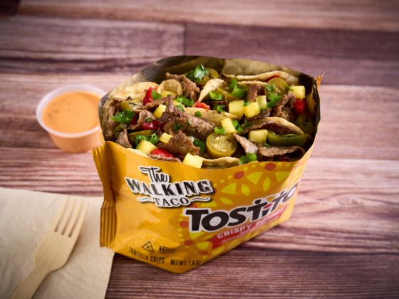 Yellow taco chip bag filled with steak, jalapenos, veggies and a orange sauce
