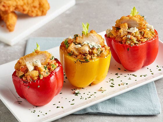 Three red and yellow bell peppers stuffed with fried chicken tenderloins and farro