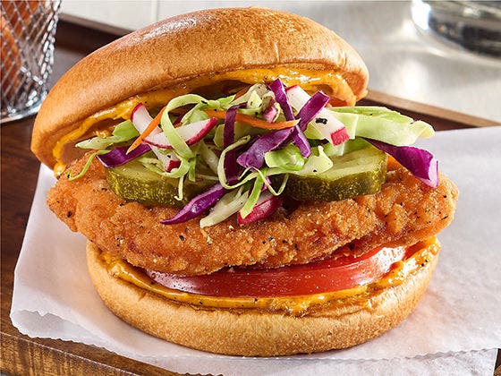 Chicken sandwich with slaw, pickles and tomato on brioche bun