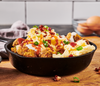 Loaded Tots in a Cast Iron Skillet Sitting on Butcher Block Counter Top