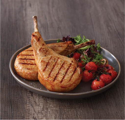 Pork Tomahawk With Side of Tomatoes on a Gray Round Plate