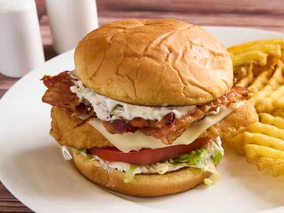 Crispy Chicken Bacon Swicy Ranch Sandwich on a plate with a side of fries.