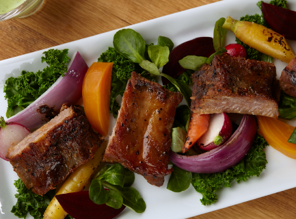 Smoked baby back ribs plated on white plate with salad and veggies