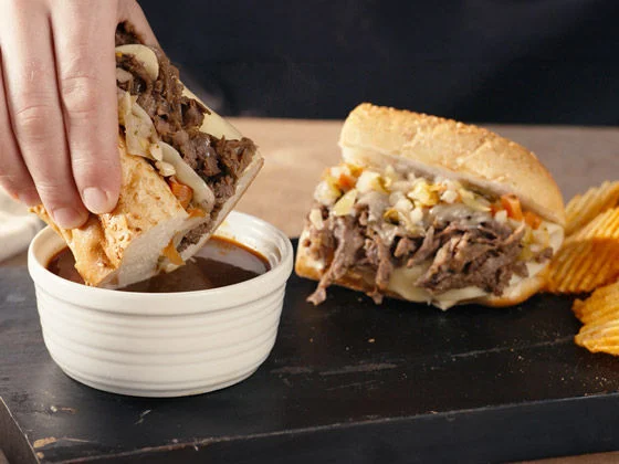 Italian beef sandwich being dipped in beef broth