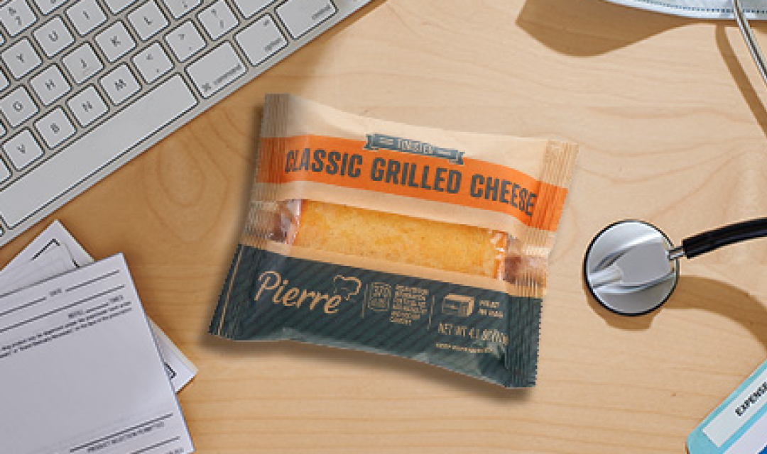 Packaged grilled cheese sandwich on a desk with keyboard and statoscope 